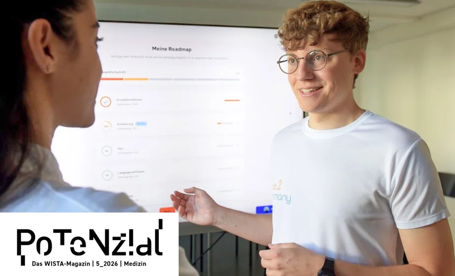 Zwei Personen im Gespräch vor einem Bildschirm mit einer Roadmap, eine Person trägt ein weißes T-Shirt und Brille